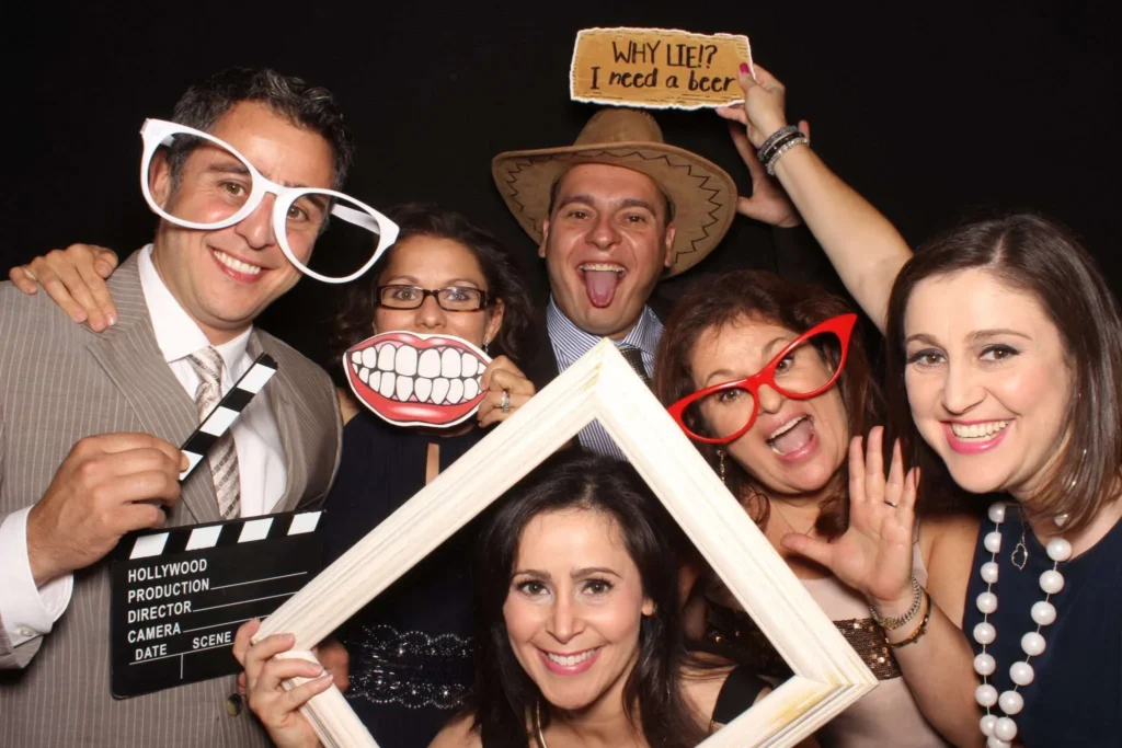 Group of guests enjoying a photo booth with funny props and signs at an event